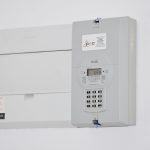 Medidor de energia elétrica e caixa de fusíveis instalados em uma parede branca.