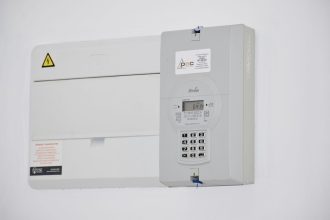 Medidor de energia elétrica e caixa de fusíveis instalados em uma parede branca.