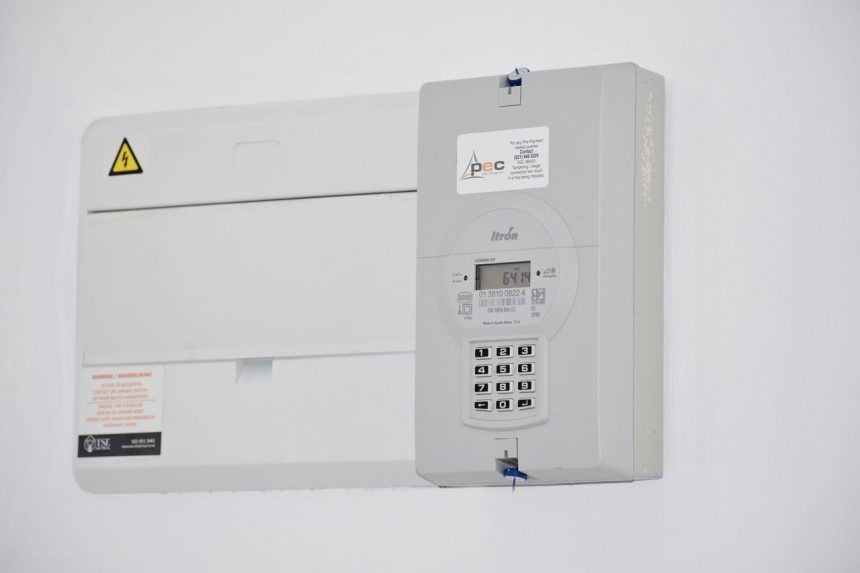 Medidor de energia elétrica e caixa de fusíveis instalados em uma parede branca.