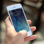 Pessoa segura um smartphone e toca na tela para consultar informações.