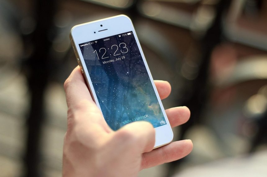 Pessoa segura um smartphone e toca na tela para consultar informações.